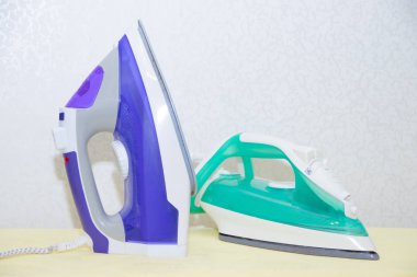 Ütü tahtasında iki ütü. Demirlerin seçimi ve karşılaştırılması. Ütü tahtası.