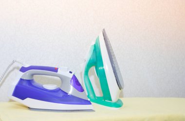 Ütü tahtasında iki ütü. Demirlerin seçimi ve karşılaştırılması. Ütü tahtası.