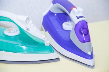 Ütü tahtasında iki ütü. Demirlerin seçimi ve karşılaştırılması. Ütü tahtası.