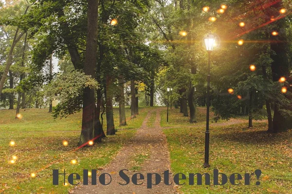 Hello September banner. New month. Greeting card. Golden autumn. The text in the photo. Trees in the park. City Park. Autumn Park