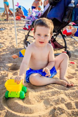 Bir çocuk sahilde daktilo çalıyor. Çocuk oyunları. Yazın plaj. Küçük çocuk