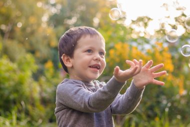 Sokaktaki bir çocuk sabun köpüğü yakalar. Mutlu çocukluk. Çocuk oyunları.