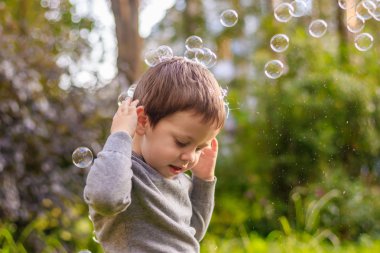 Sokaktaki bir çocuk sabun köpüğü yakalar. Mutlu çocukluk. Çocuk oyunları.