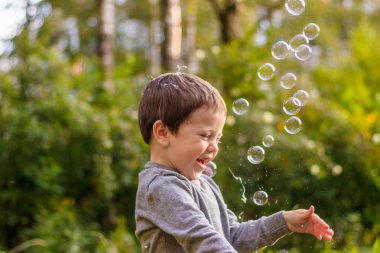 Sokaktaki bir çocuk sabun köpüğü yakalar. Mutlu çocukluk. Çocuk oyunları.