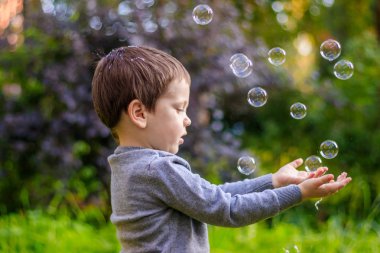 Sokaktaki bir çocuk sabun köpüğü yakalar. Mutlu çocukluk. Çocuk oyunları.