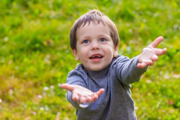 Um rapaz na rua apanha bolhas de sabão. Feliz infância. Jogos infantis . — Fotografia de Stock