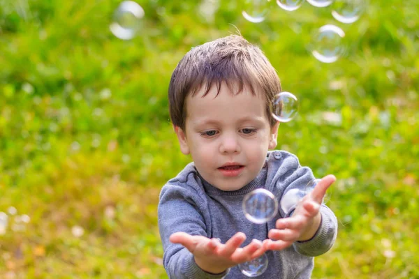 A boy on the street catches soap bubbles. Happy childhood. Childrens games. Royalty Free Stock Photos