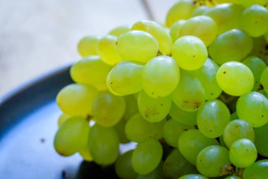 Tabakta bir dal yeşil üzüm üzümü. Tabakta meyve var. Yeşil çilek.