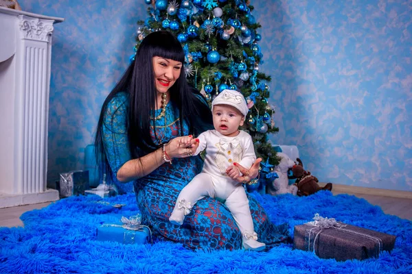 Mutter und Sohn sitzen unter dem Neujahrsbaum. Weihnachtsfamilie. Neujahrsferien. geschmückter Weihnachtsbaum. — Stockfoto