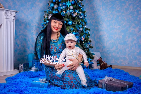 A mãe e o filho estão sentados debaixo da árvore de Ano Novo. Família de Natal. Férias de Ano Novo. Vestido até árvore de Natal . — Fotografia de Stock