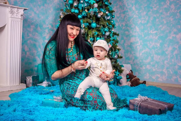 Máma a syn sedí pod stromem Nového roku. Vánoční rodina. Novoroční prázdniny. Oblečený vánoční stromek. — Stock fotografie