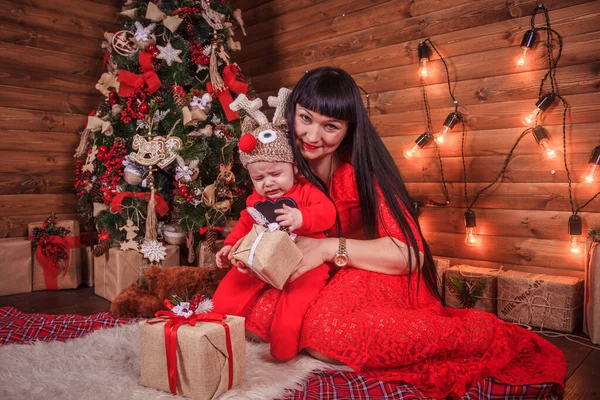 Anne ve oğlu yeni yıl ağacının altında oturuyorlar. Noel ailesi. Yeni yıl tatili. Giyinik Noel ağacı. — Stok fotoğraf