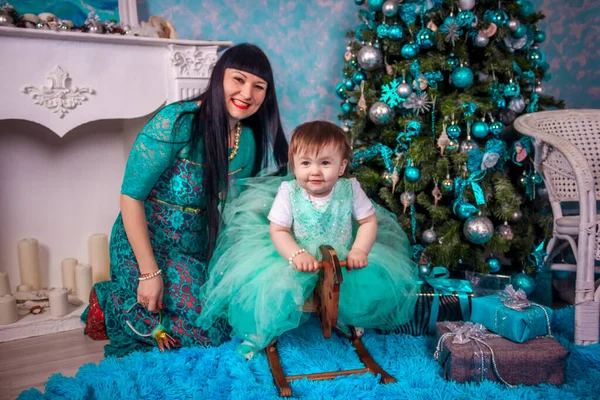 Mutter und Tochter sitzen unter dem Neujahrsbaum. Weihnachtsfamilie. Neujahrsferien. geschmückter Weihnachtsbaum. — Stockfoto