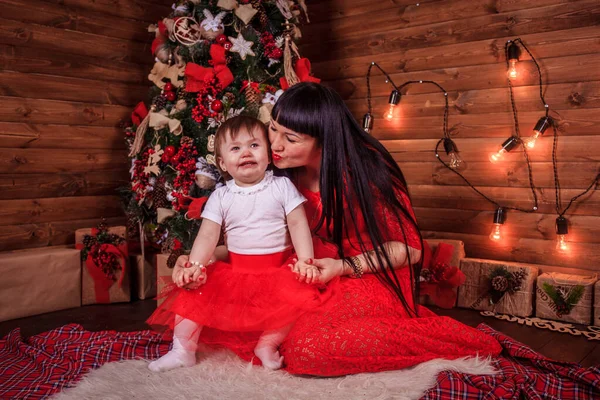 Maman et fille sont assises sous le sapin du Nouvel An. Famille de Noël. Vacances du Nouvel An. Habillé arbre de Noël . — Photo