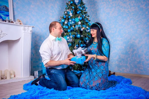 Mann und Frau sitzen unter dem Neujahrsbaum. Weihnachtsfamilie. Neujahrsferien. geschmückter Weihnachtsbaum. — Stockfoto
