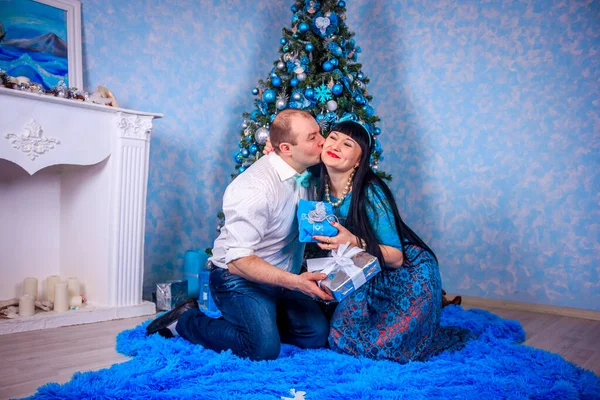 Mann und Frau sitzen unter dem Neujahrsbaum. Weihnachtsfamilie. Neujahrsferien. geschmückter Weihnachtsbaum. — Stockfoto