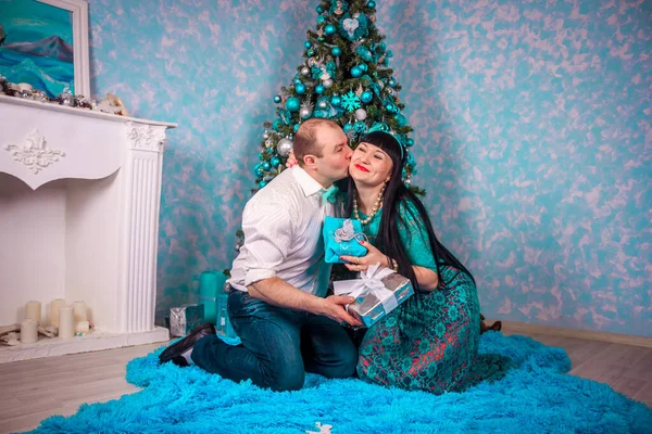 Mann und Frau sitzen unter dem Neujahrsbaum. Weihnachtsfamilie. Neujahrsferien. geschmückter Weihnachtsbaum. — Stockfoto