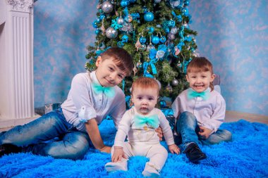 Noel ağacı arka planında üç kardeş, yeni yıl tatili konsepti 