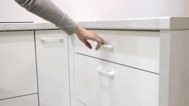Eine Frauenhand öffnet eine Schublade im Küchentisch. Helle Küche. Ausziehbare Küchenschubladen. Schachteln mit Verschlüssen. Moderne Möbelbeschläge. . Russland, Sankt Petersburg 10. Juli 2020 — Stockvideo