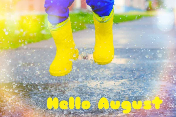 水たまりの中のゴムブーツ 水からのスプレー 夏の雨 写真デザインは英語で書かれています こんにちは8月のバナーこんにちは新しい月 英語で挨拶 8月の夏 — ストック写真