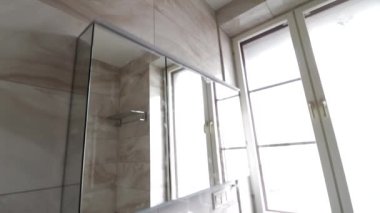 Musluktan su akar. Beyaz kabuk. Banyonun iç kısmı. Pencerenin yanında lavabo var. El yıkama..