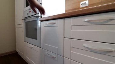 Hareket halindeki modern bir ışık mutfağının detayları. Parlak mutfak manzarası. Mutfak vitrini. Videoda hareket var. Mutfak beyaz ve ahşap tezgahı var. Rusya, Saint Petersburg, İç Kesimler