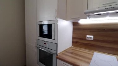 Hareket halindeki modern bir ışık mutfağının detayları. Parlak mutfak manzarası. Mutfak vitrini. Videoda hareket var. Mutfak beyaz ve ahşap tezgahı var. Rusya, Saint Petersburg, İç Kesimler