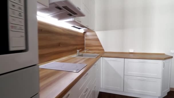Details of a modern light kitchen in motion . View of the bright kitchen . Kitchen display. Movement in the video the kitchen is white with a wooden countertop. Russia, Saint Petersburg, Interior of a — Stock Video