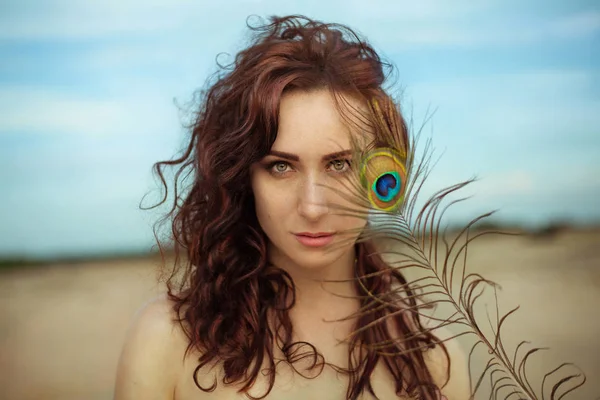 Mooie jongedame in woestijn met peacock feather — Stockfoto