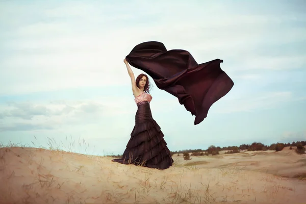 Jovem mulher bonita no deserto em vestido preto — Fotografia de Stock