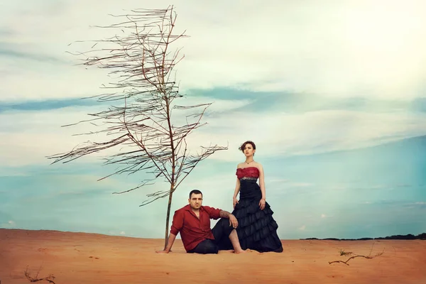 Homem de camisa e mulher de vestido no deserto em backgroun do céu — Fotografia de Stock