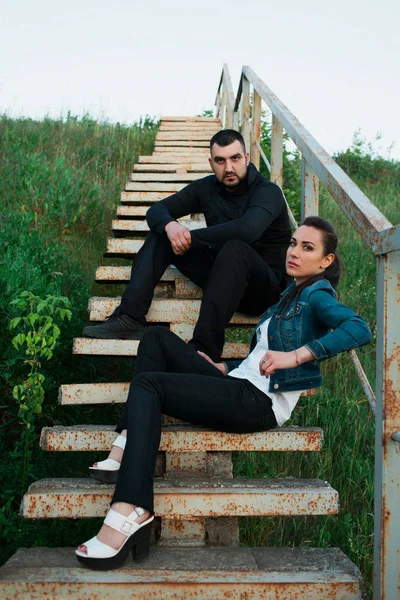 Jovem homem e mulher em escadas no fundo da natureza e do céu — Fotografia de Stock