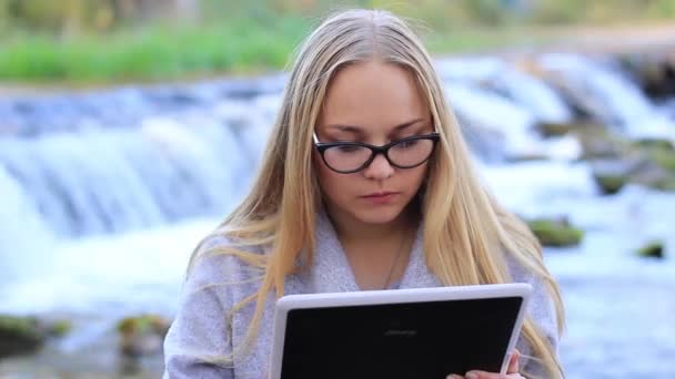 Krásná dívka blízko vodopádu s tabletem — Stock video