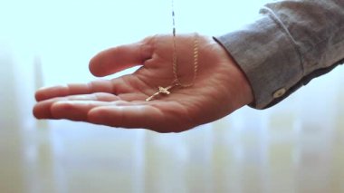 bir haç ile altın bir zincir tutan erkek el