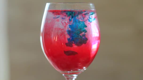 Vidrio con agua con pintura roja y azul . — Vídeos de Stock