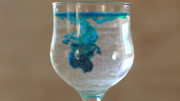 Glas mit Wasser mit blauer Farbe. — Stockvideo