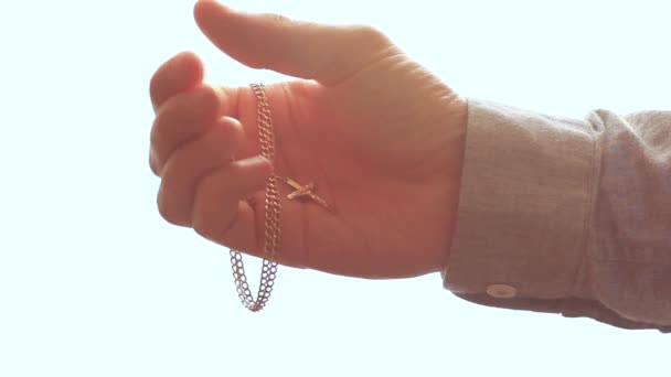 Male hand holding a gold chain with a cross — Stock Video