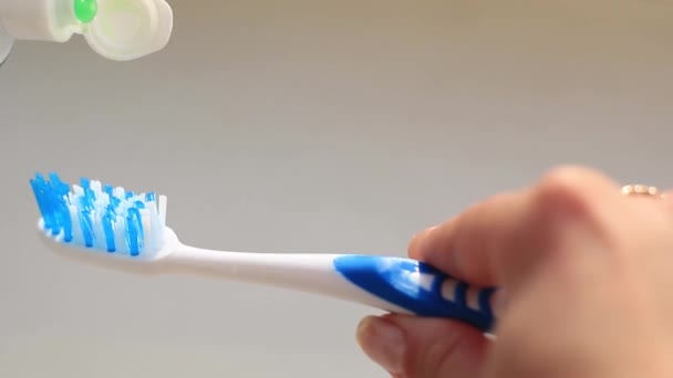 La mano femenina unta la pasta de dientes en un cepillo de dientes — Vídeo de stock