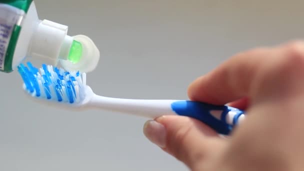 Female hand smears toothpaste on a toothbrush — Stock Video