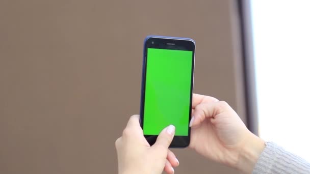 Female hands are holding a mobile device with a green screen. Chrome key — Stock Video