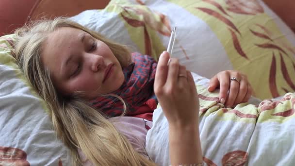 Menina doente encontra-se na cama e mede a temperatura — Vídeo de Stock