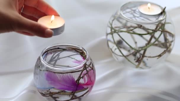 Frauenhand steckt eine Kerze in einen Kolben mit Wasser und Dekorationen — Stockvideo