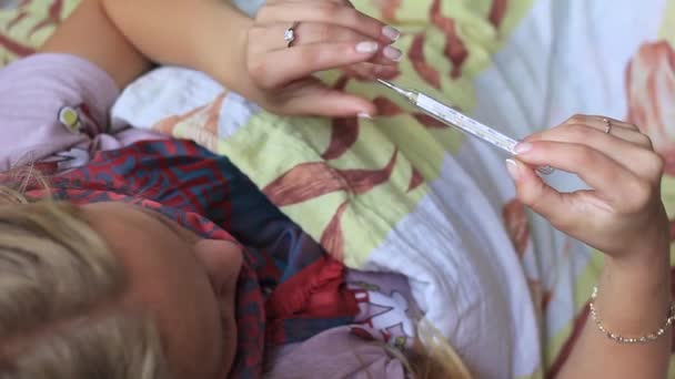 Fiatal lány influenza és úgy néz ki, a hőmérő — Stock videók
