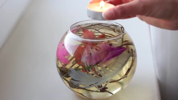 Женская рука кладет свечу во фляжку с водой и украшениями — стоковое видео