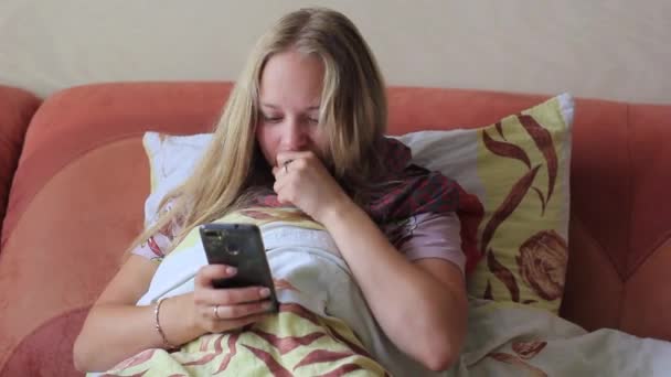 Νεαρό κορίτσι bollet και χρησιμοποιεί το τηλέφωνο στο κρεβάτι — Αρχείο Βίντεο
