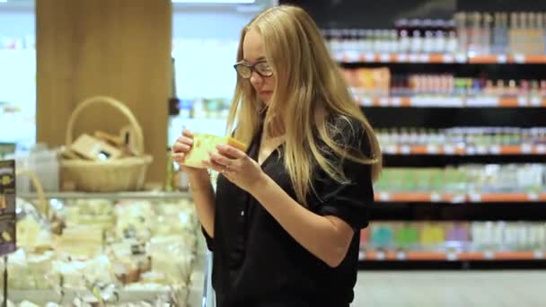 Kız peynir süpermarkette seçer. — Stok video