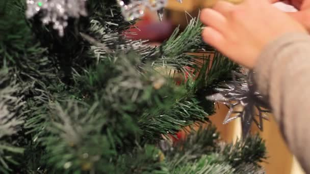 Año Nuevo. La mano femenina pone juguetes en el árbol de Navidad . — Vídeo de stock