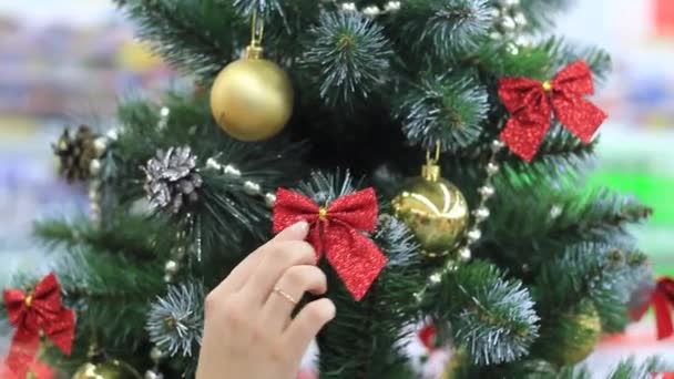 Neujahr. Weibliche Hand legt Spielzeug auf den Weihnachtsbaum. — Stockvideo
