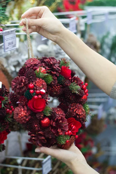 Female hands are considering a handmade work christmas wreath