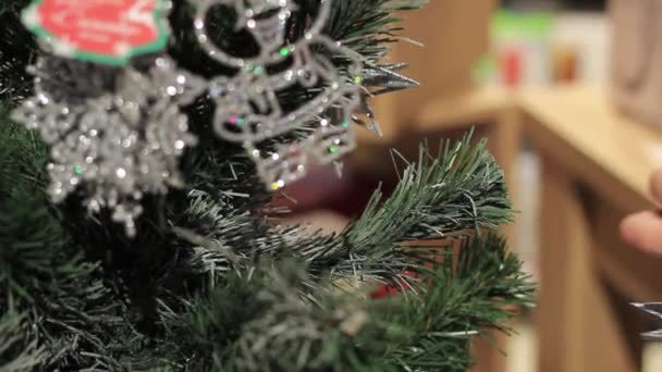 Año Nuevo. La mano femenina pone juguetes en el árbol de Navidad . — Vídeo de stock